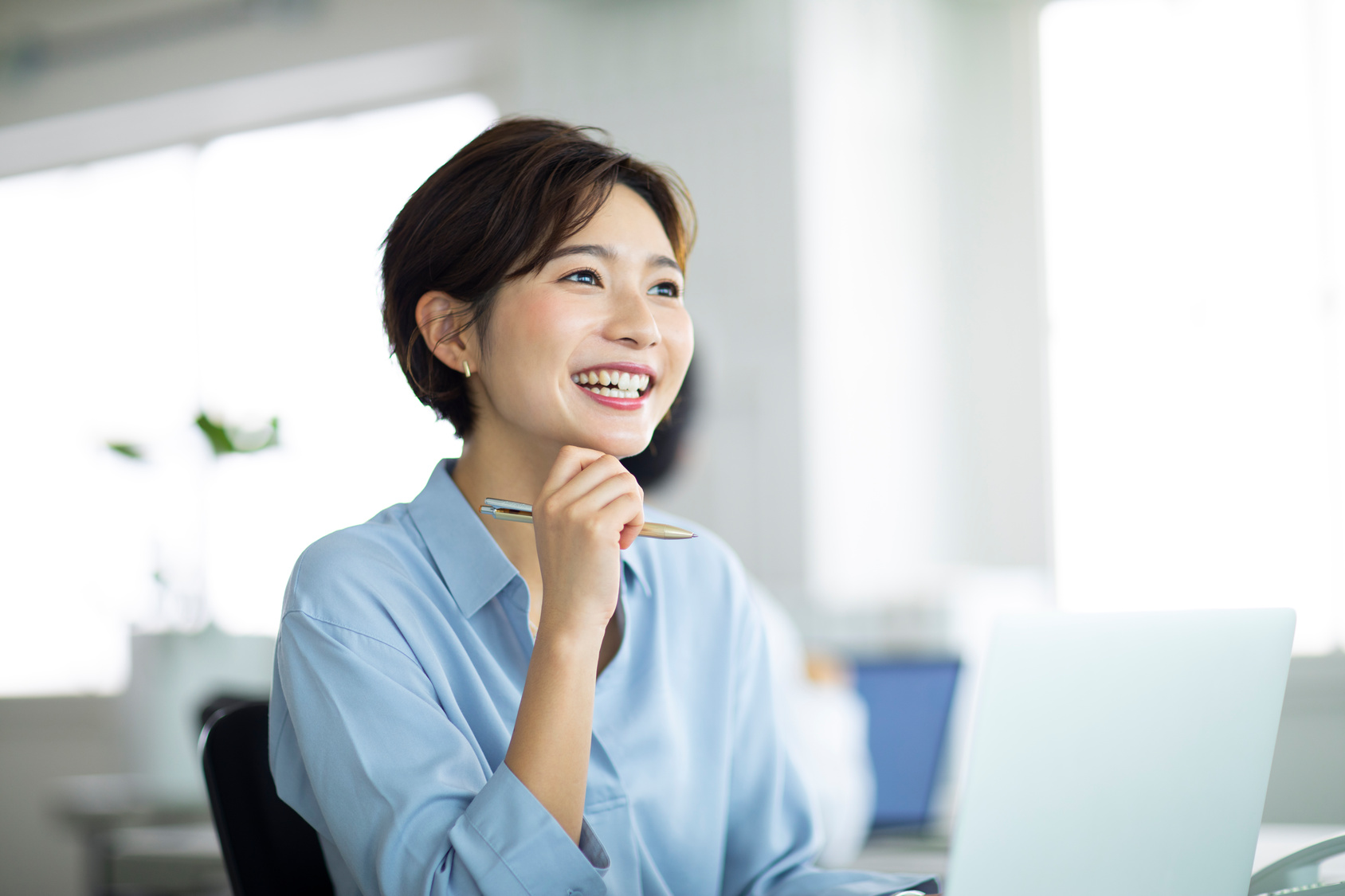 女性がペンを持って微笑んでいる様子